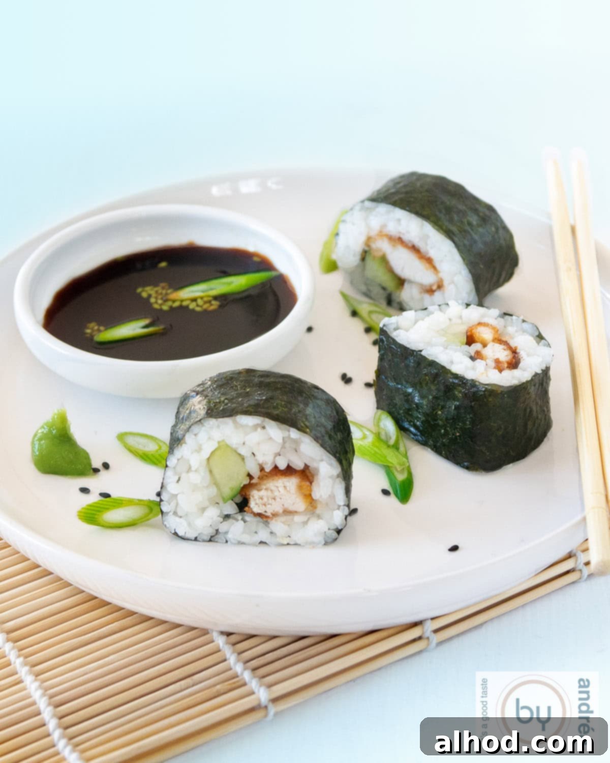 Kentucky Sushi: A Bold New Roll 2 A white plate with three perfectly rolled sushi pieces, showcasing the crispy chicken and fresh cucumber filling, served with a side of soy sauce on a blue background.