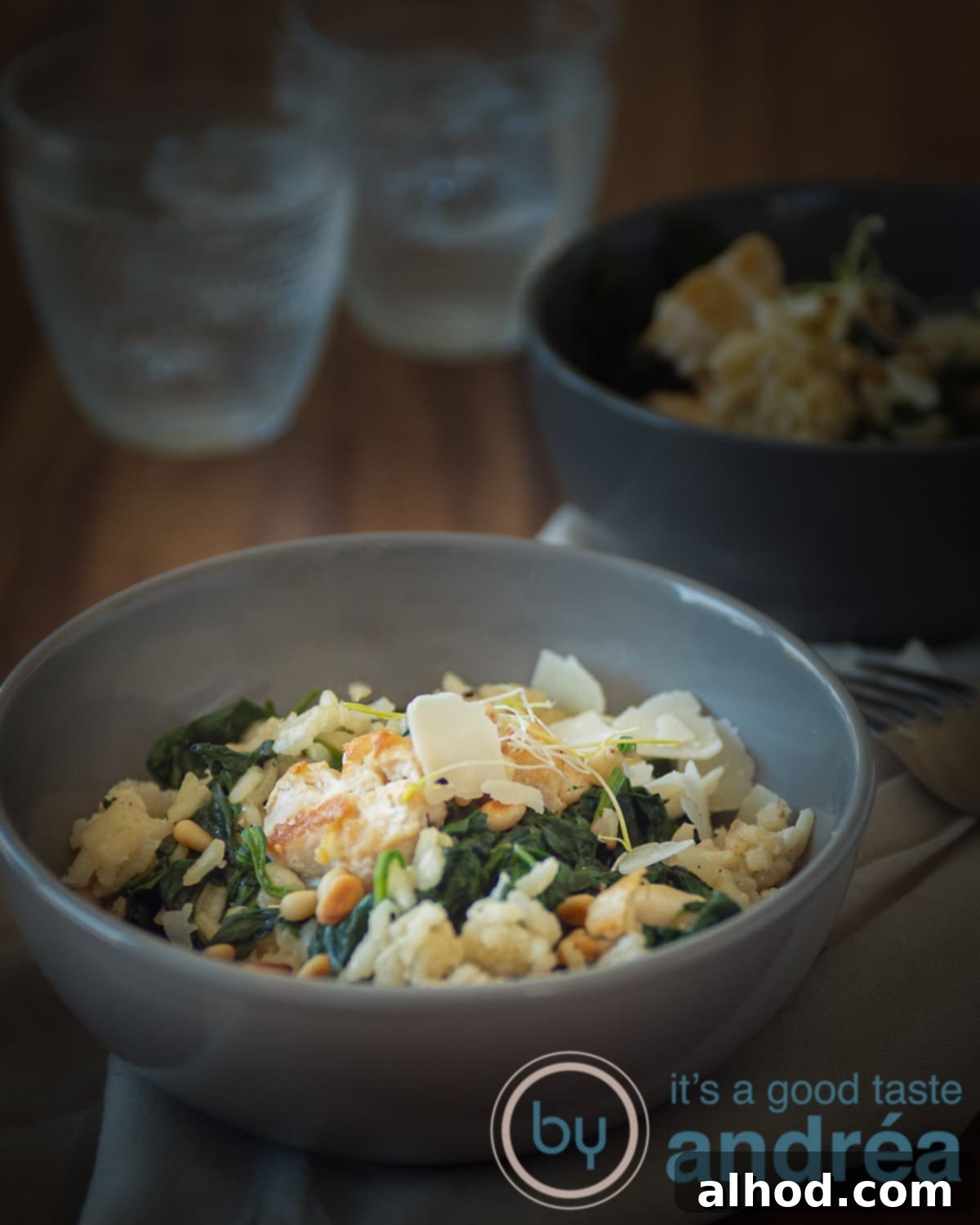 Creamy Chicken and Spinach Risotto 4 a grey bowl filled with creamy risotto with spinach and chicken. Another bowl in the back as are two glasses