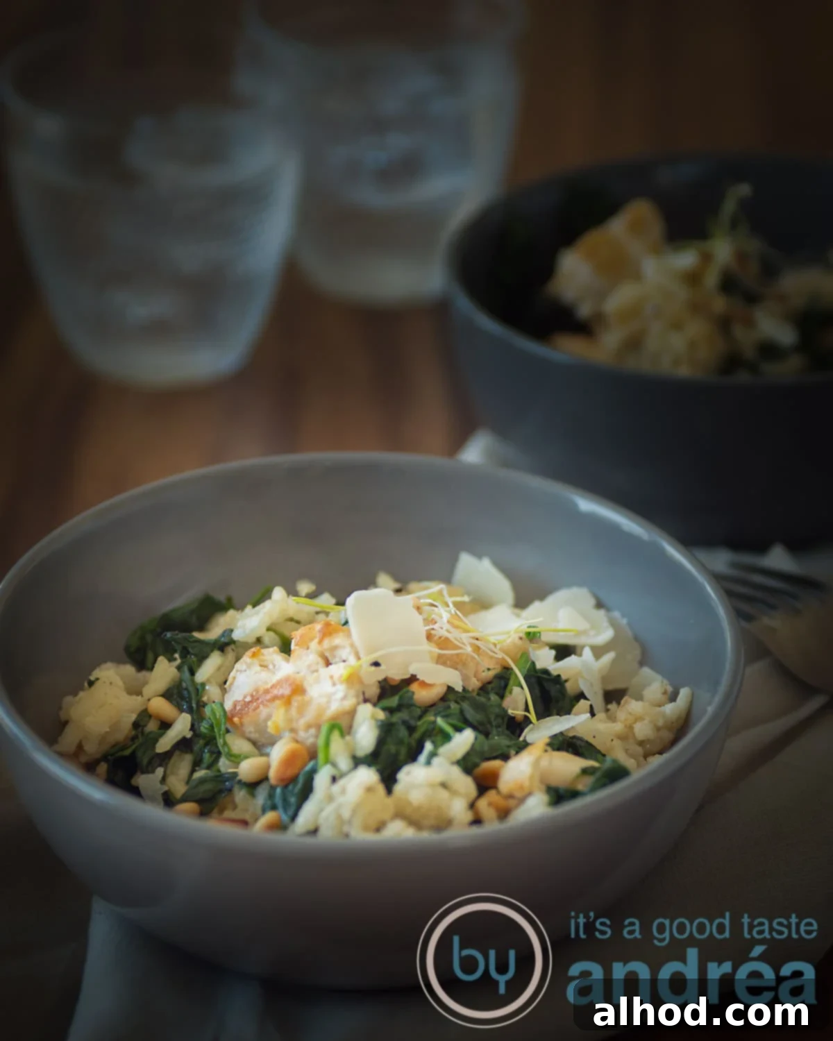 Creamy Chicken and Spinach Risotto 5 a grey bowl filled with creamy risotto with spinach and chicken. Another bowl in the back as are two glasses