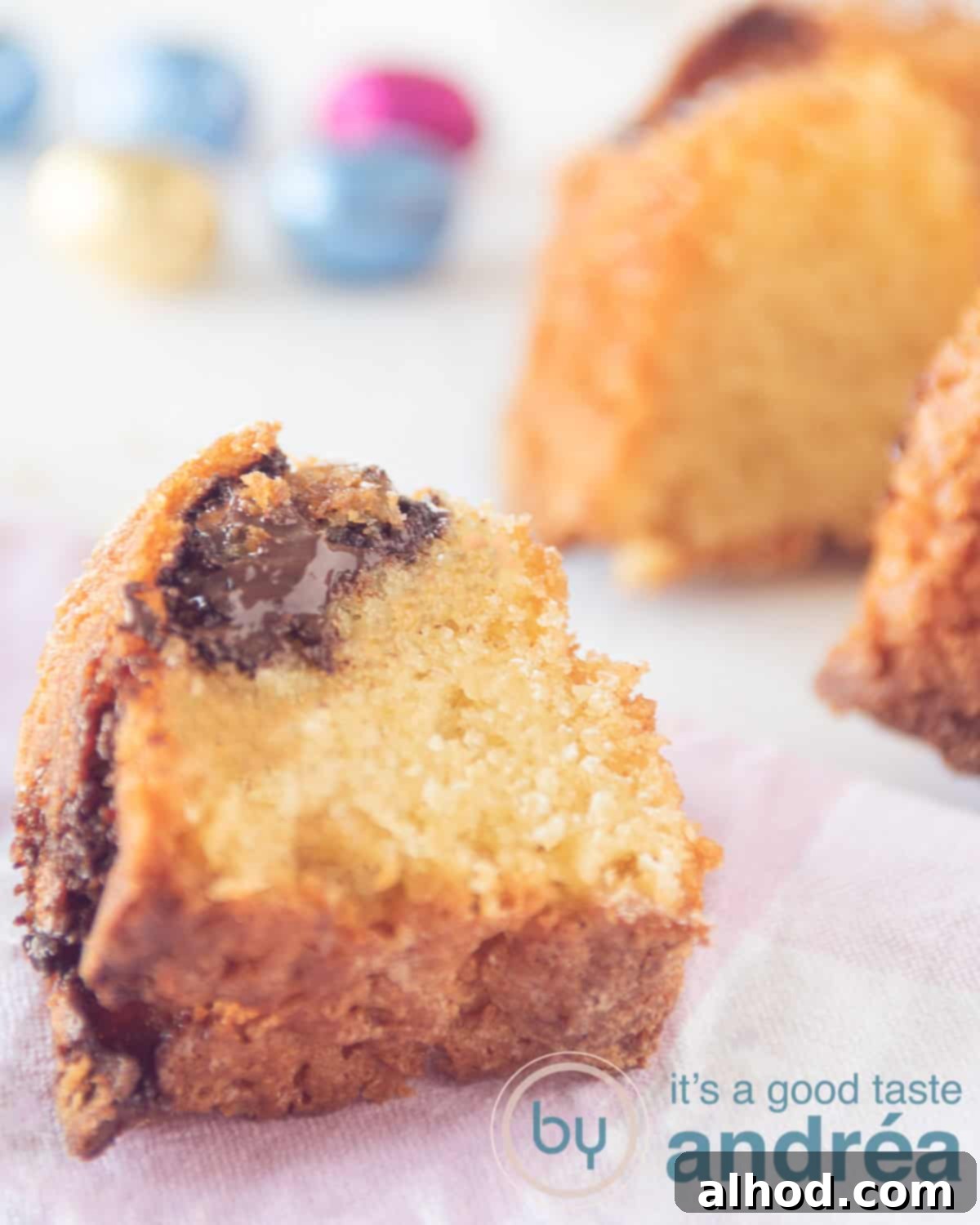 Easter Bundt Cake with Chocolate Egg Surprises 2 A slice of Easter Bundt cake revealing hidden chocolate eggs, with a full cake and more chocolate eggs in the background.