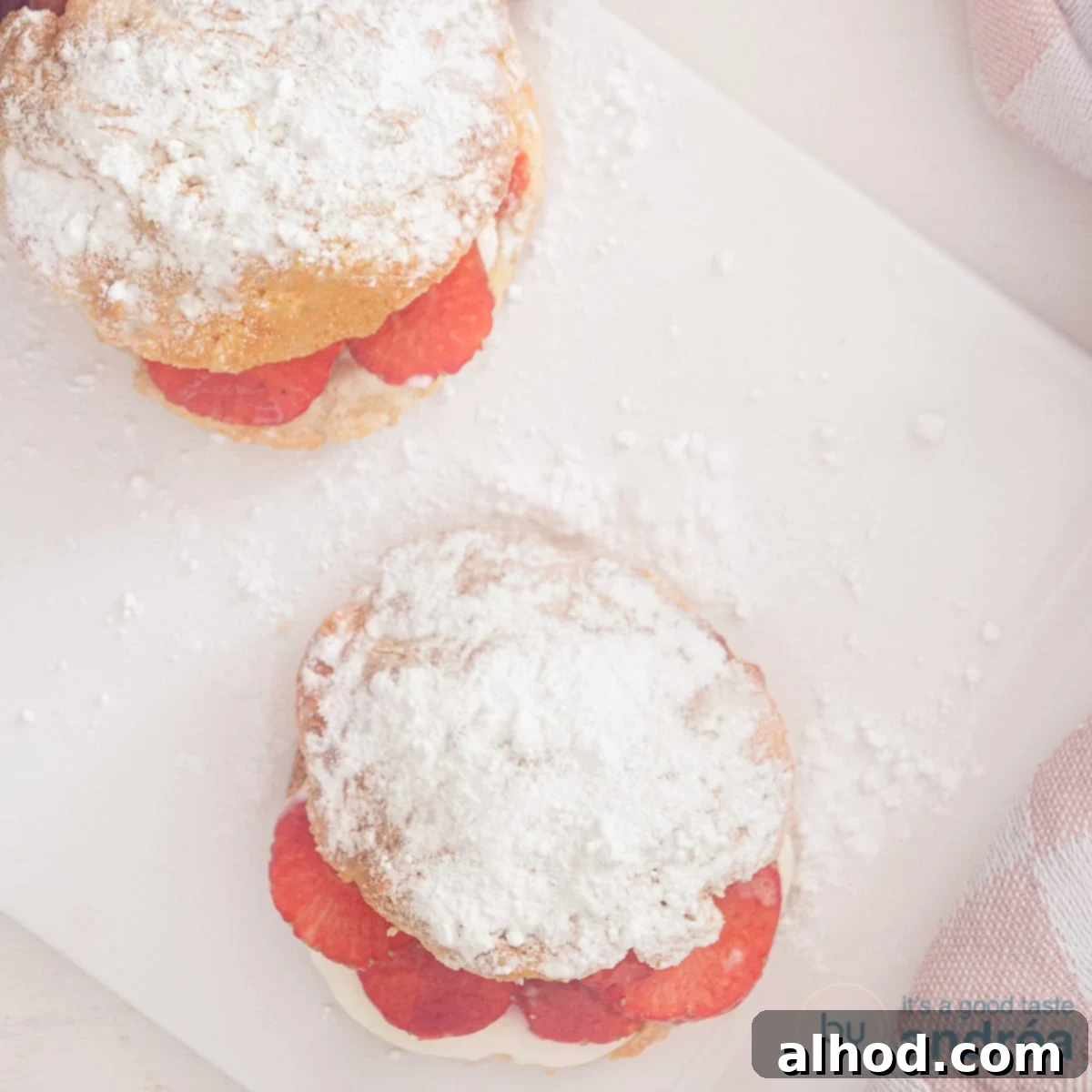 7 Scrumptious Mother's Day Brunch Recipes She'll Love 3 A square photo of two light, fluffy English scones photographed from above, served with fresh strawberries and a dollop of cream on a white background, perfect for a delightful brunch.