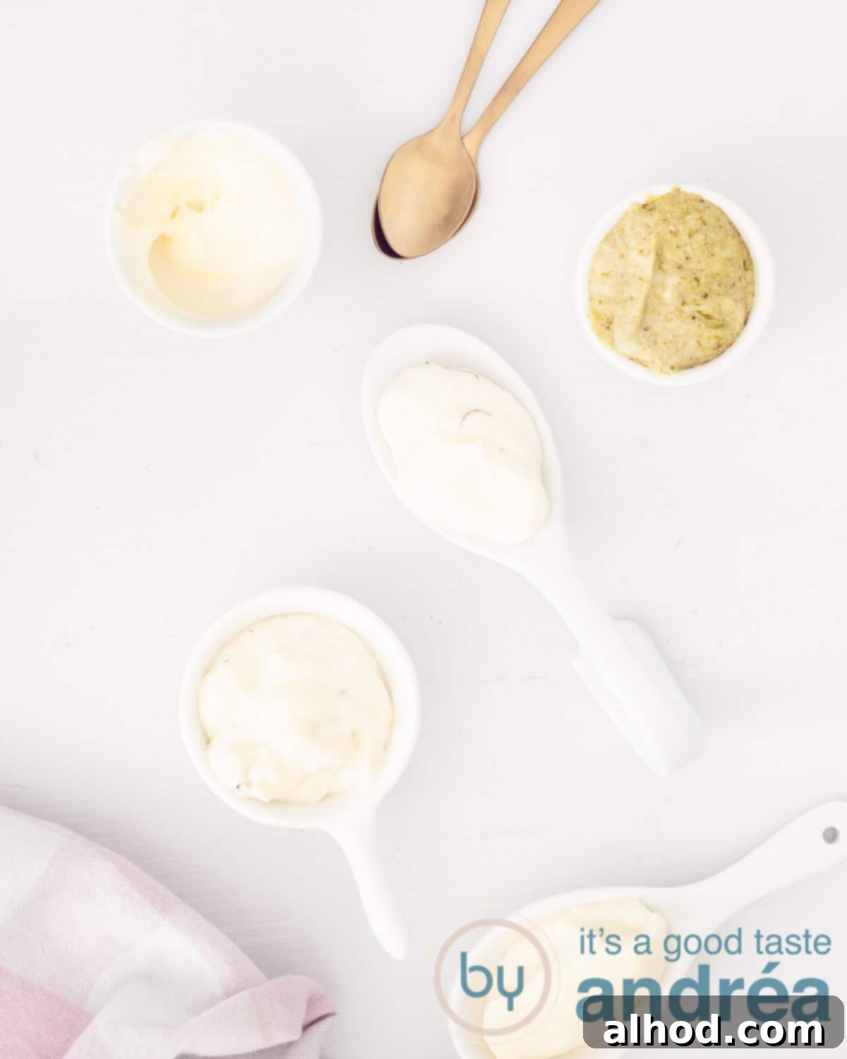 Upgrade Your Mayo: 5 Delicious Flavor Infusions 2 A photo from above with different mayonnaise variants on a white background. In the bottom corner a pink and white checkered tea towel