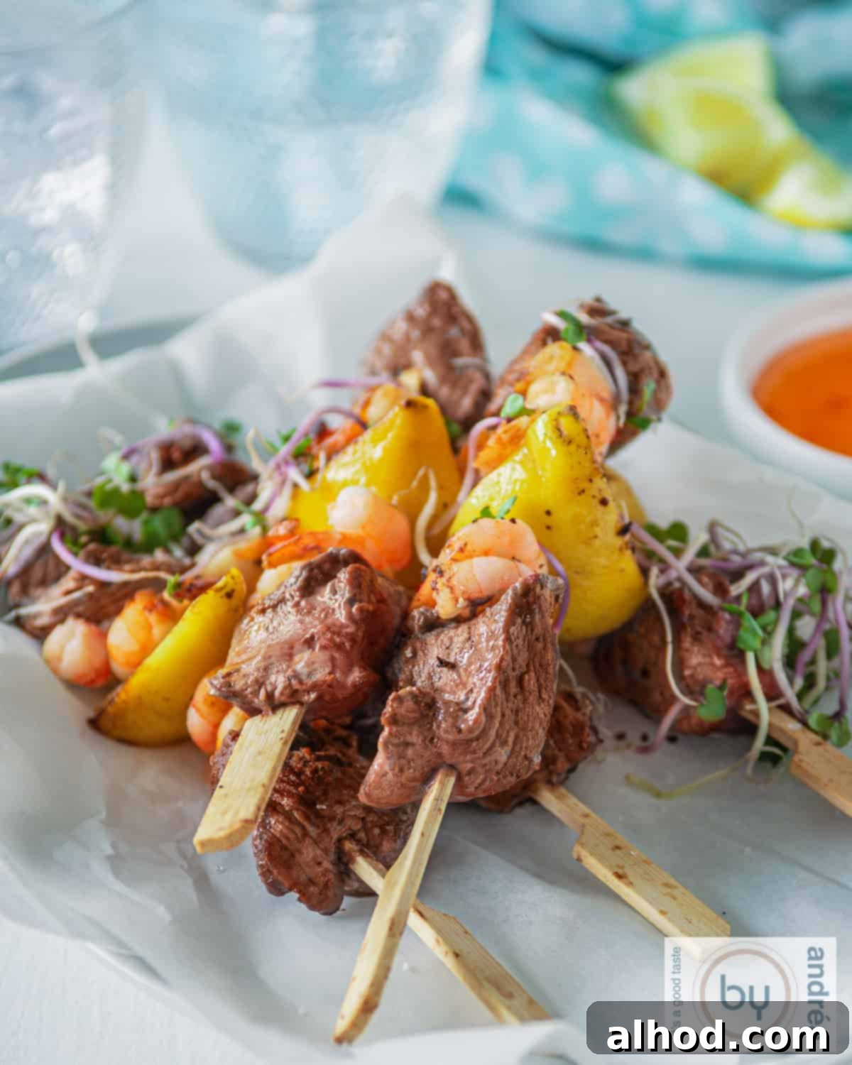 Grilled Surf and Turf Skewers 2 Five beautifully arranged surf and turf skewers on a white background, accompanied by two glasses, ready for a delightful meal.