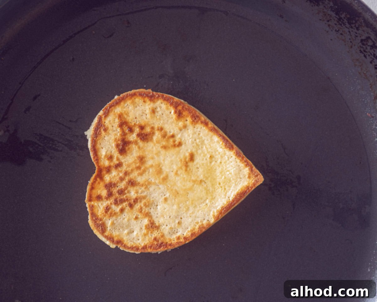Sweetheart Pancakes with Strawberry Delight 7 A frying pan with a baked heart pancake