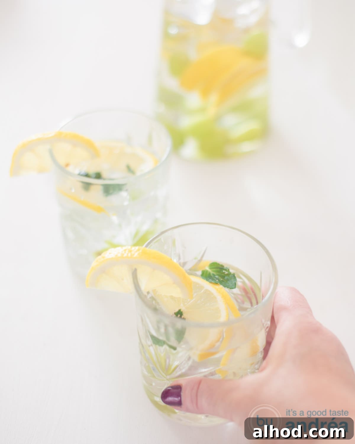 Flavorful Grape Infusion 2 Refreshing grape and lemon infused water in a tall glass, held by a hand. Perfect for healthy hydration.