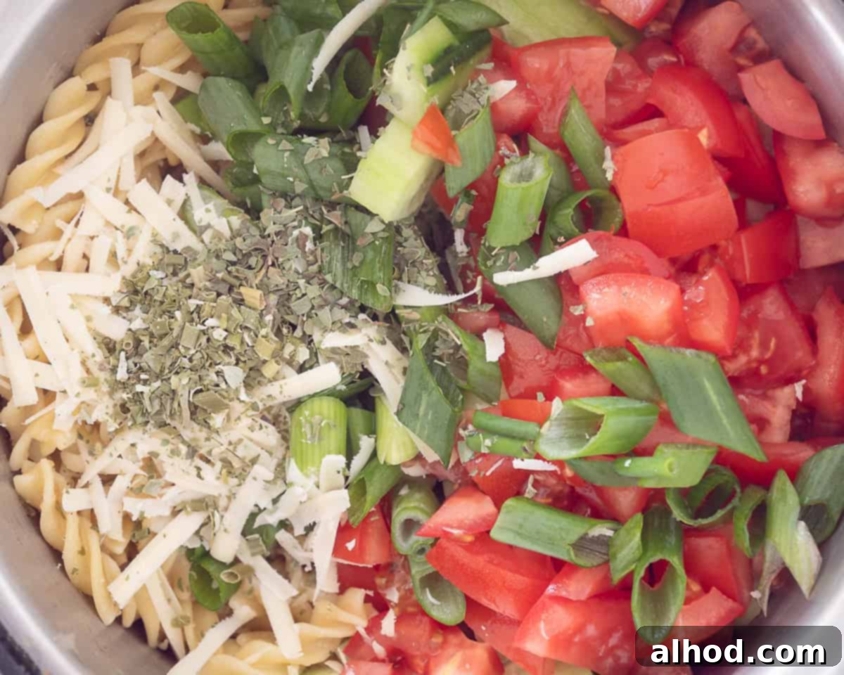 In a bowl add tomatoes, spring onions, cheese, Italian herbs, cucumber to the pasta
