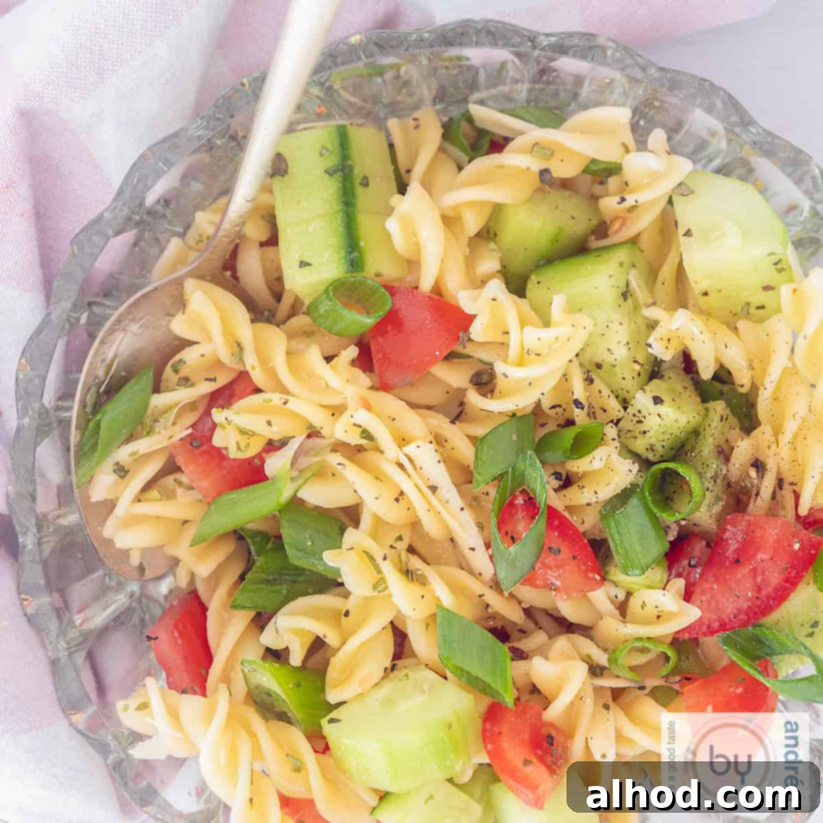 Zesty Italian Veggie Pasta Salad 10 A square picture, top side down of a glass bowl filled with fussili salad, with cucumber, spring onions, tomatoes and dressing.