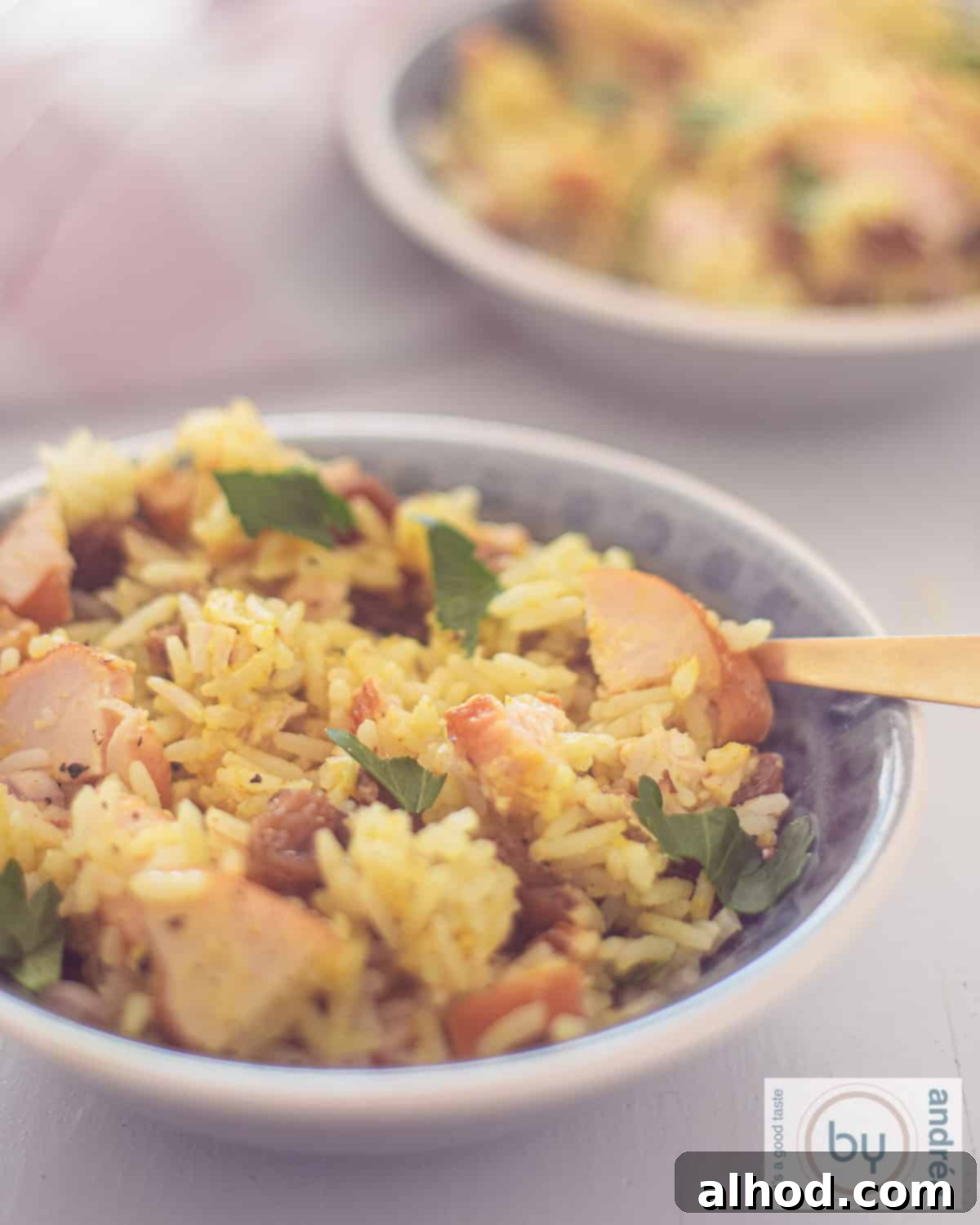 Golden Smoked Chicken and Curry Rice Medley 2 A portion of a gray bowl of curry rice with chicken, parsley, walnuts and raisins as a salad.