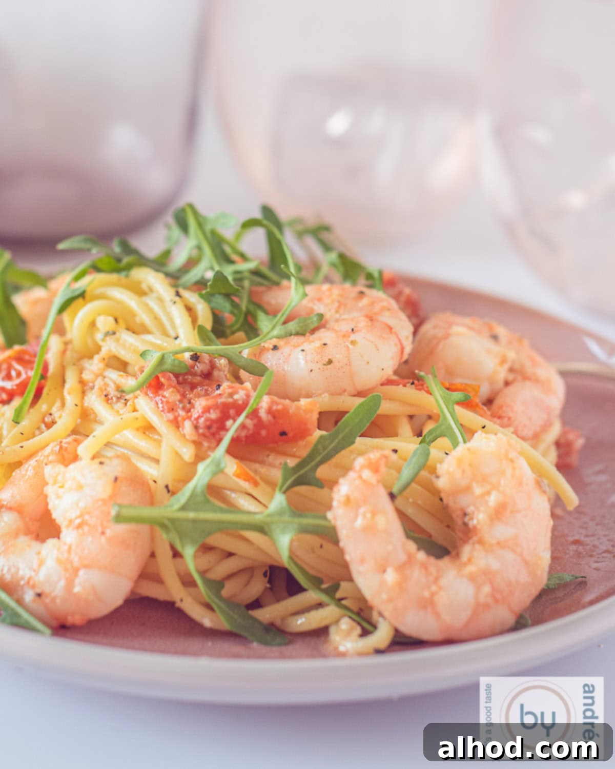 Speedy Shrimp & Arugula Spaghetti 3 A photo of a pink plate with spaghetti, arugula, shrimps and tomatoes.