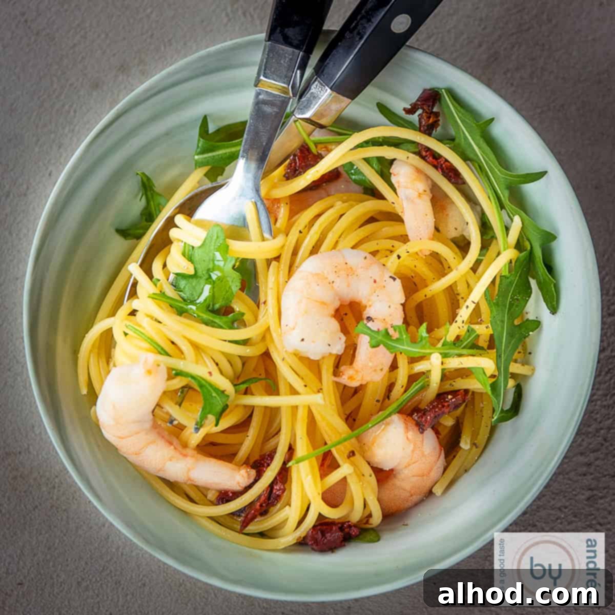 Speedy Shrimp & Arugula Spaghetti 4 A square photo with a green bowl with pasta, shrimp and arugula