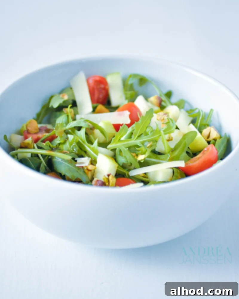 Vibrant Arugula Salad with Sweet Pear Crisp Apple and Pistachio Crunch 2 Vibrant arugula salad with pear, pistachios, apple slices, and grated aged cheese, drizzled with a delicious dressing.