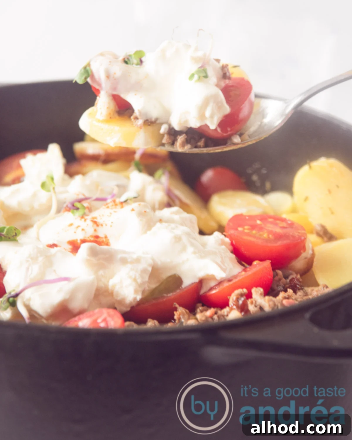 Hearty Greek Beef and Potato Bake 5 Greek potato dish with minced meat in a black pan. A spoon takes out a scoop.