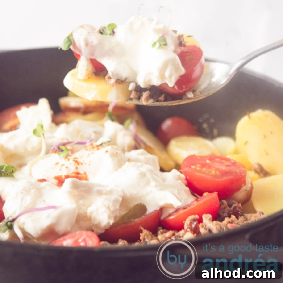 Hearty Greek Beef and Potato Bake 6 A square shot of a black skillet filled with a Greek stew with minced meat and yogurt cheese topping. A spoon takes out a bite.