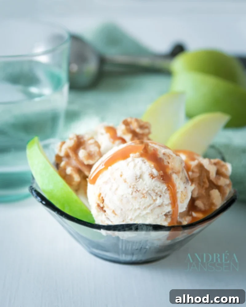 Easy Apple Pie Ice Cream 5 A black glass bowl with apple pie icecream, walnuts, slices of apple and caramel sauce. In the background an ice ream scoop and some more apples