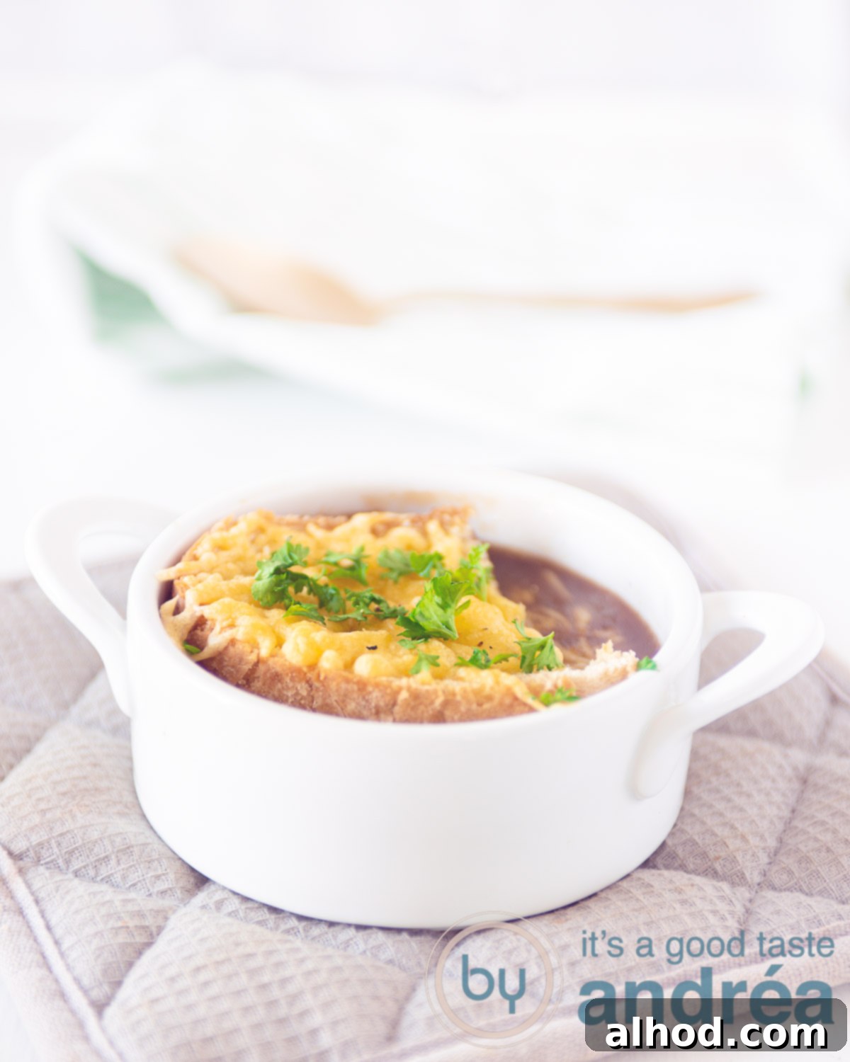 Caramelized Red Onion Soup with Crispy Cheese Toast 5 A single bowl of French onion soup, elegantly topped with a grilled cheese baguette, ready to be enjoyed.