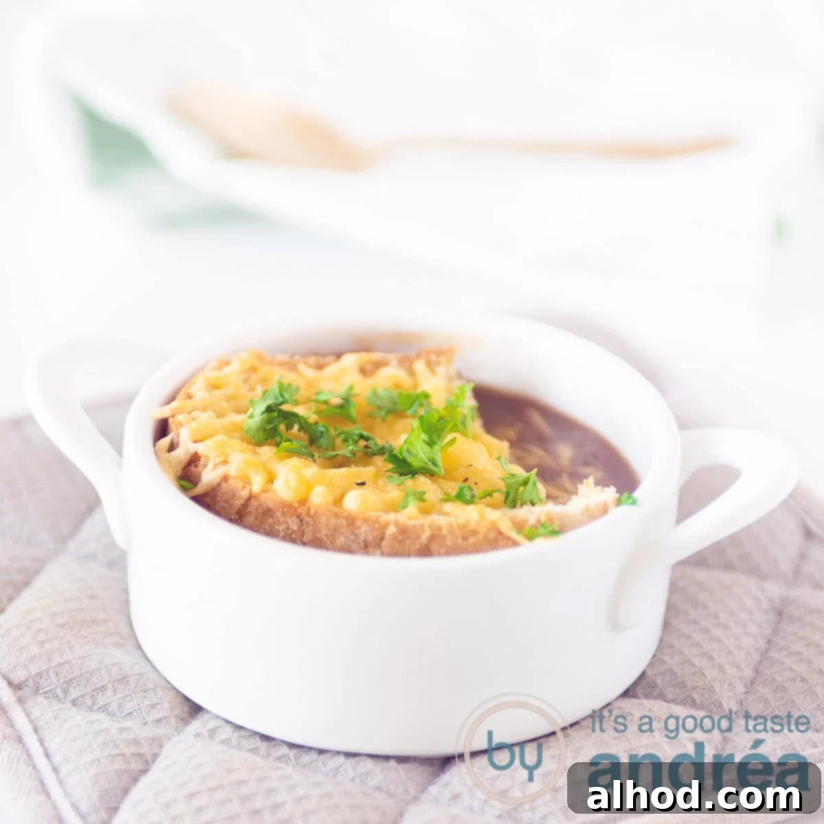 Hearty Red Onion Soup with Cheesy Toast 6 A white soup bowl filled with delicious red onion soup and a piece of gratinated baguette topped with melted Gruyère cheese, ready to be served.