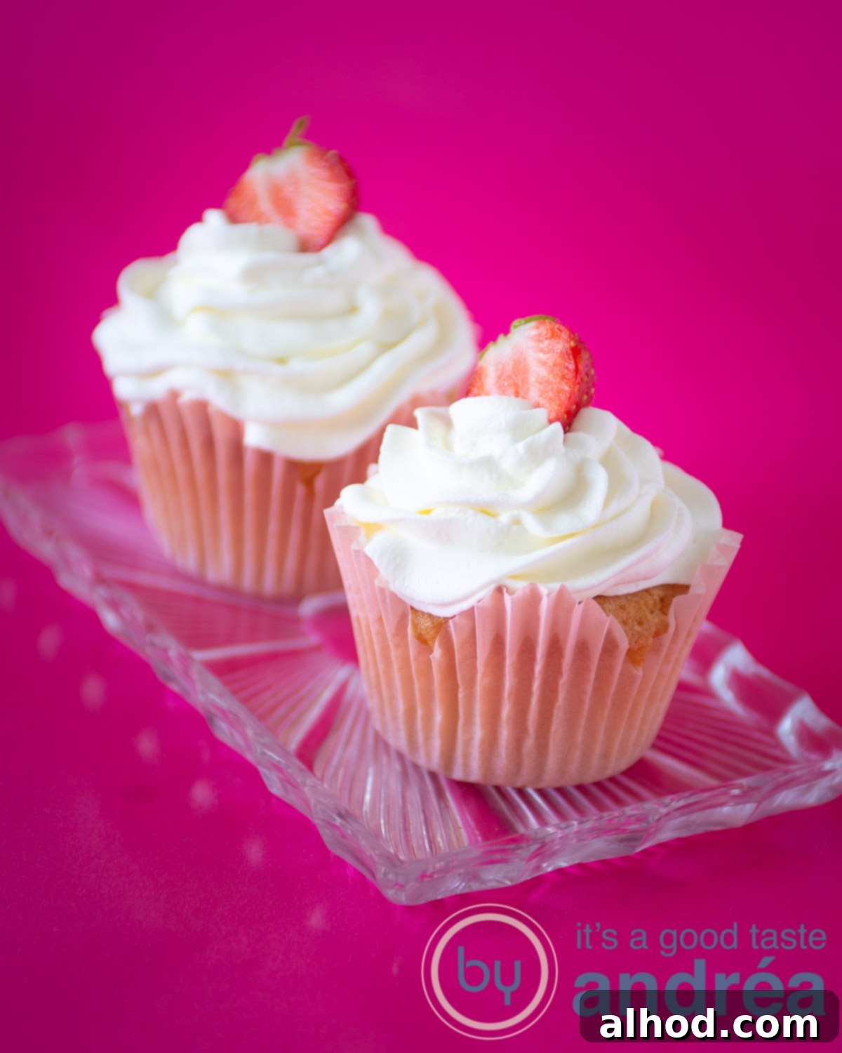 Sweet Strawberry Bliss Cupcakes 2 Two strawberry filled cupcakes on a glass plate, garnished with fresh strawberries