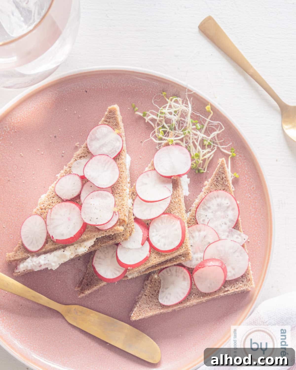 Crisp Radish Tea Sandwiches on Hearty Rye 2 A height picture taken from above. A pink plate with three sandwiches with radish spread.