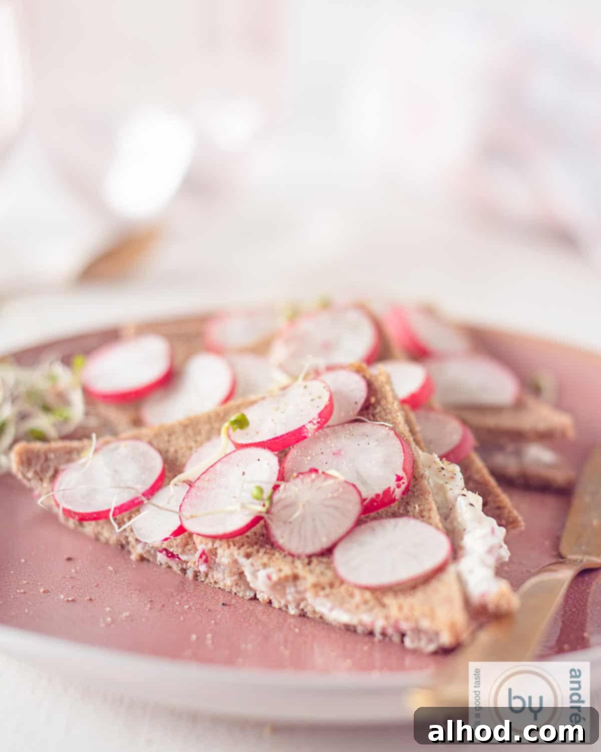 Crisp Radish Tea Sandwiches on Hearty Rye 3 A height picture of a pink plate with three radish tea sandwiches on top.