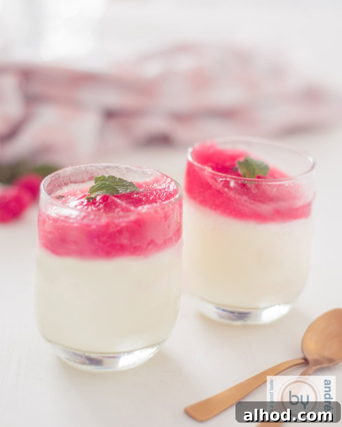 Frosted Lime Yogurt with Raspberry Mint Glaze 2 Two glasses of yogurt ice cream with raspberries and mint on a white background.