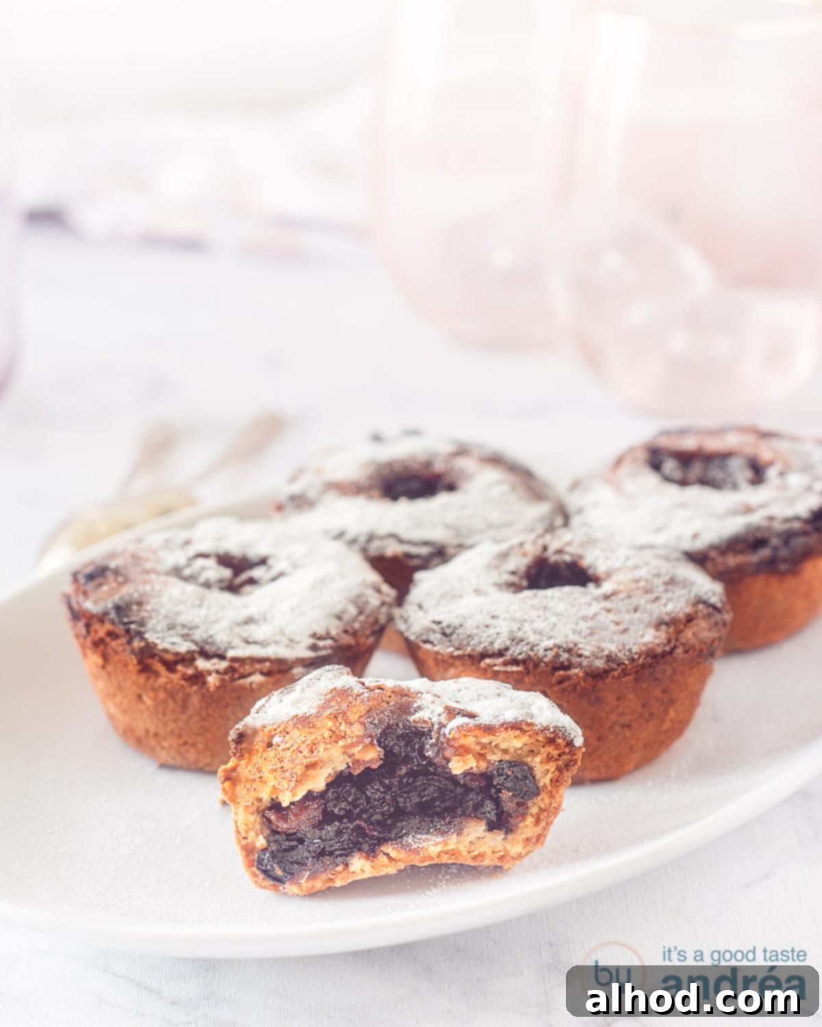 Decadent Hazelnut Mince Pies 2 Five fruit mince pies on a white plate, beautifully dusted with powdered sugar, ready to be served.
