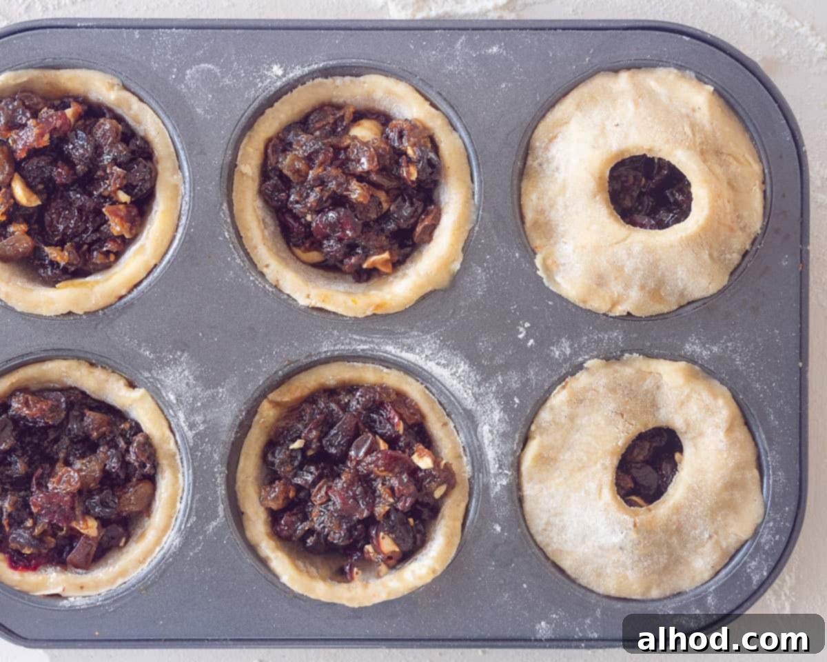 Decadent Hazelnut Mince Pies 8 A muffin baking form with filled dough with fruit mince. Two topped with extra dough, showing the decorative cutouts.