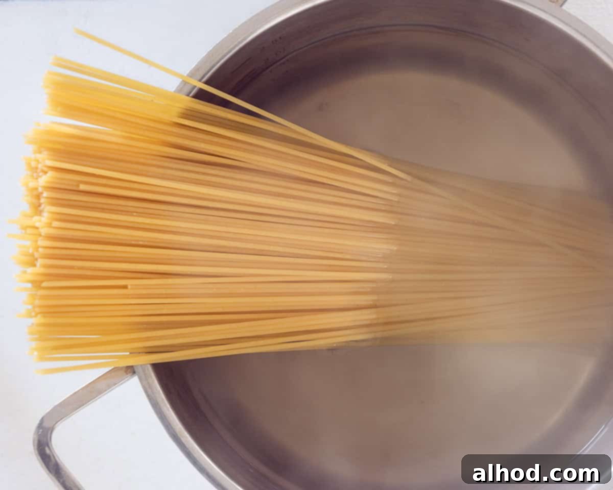 Effortless Asparagus Pasta with Poached Egg 5 A pan with uncooked spaghetti being added to boiling water