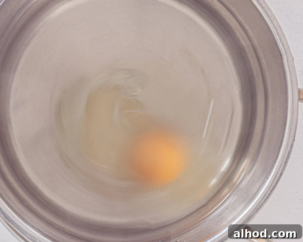 Effortless Asparagus Pasta with Poached Egg 6 A pan with water and vinegar and an egg for poaching, creating a whirlpool