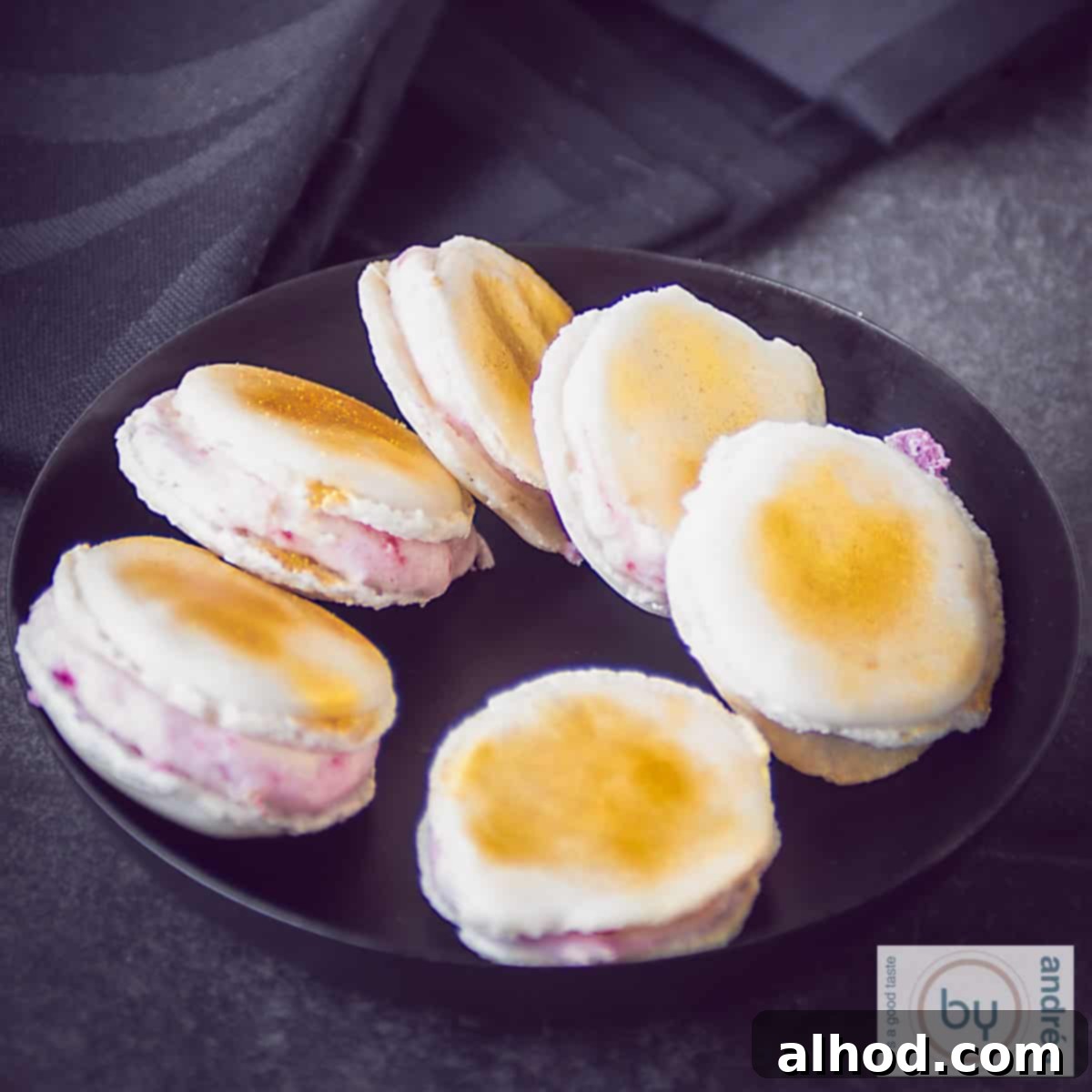 Homemade Macaron Trio: Three Delicious Flavors 7 Vanilla macarons with Prosecco strawberry filling on a black plate