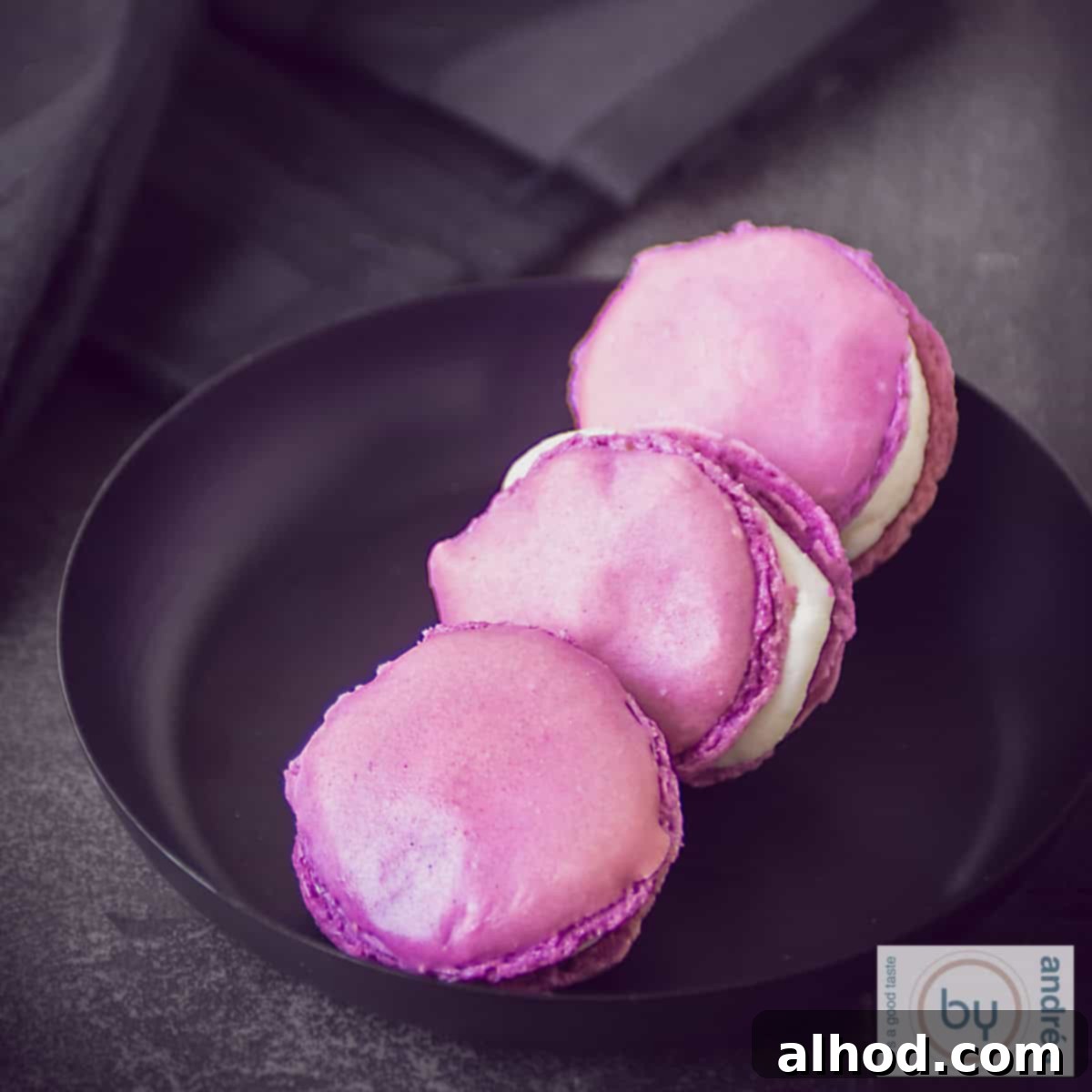 Homemade Macaron Trio: Three Delicious Flavors 3 Pomegranate macarons with Champagne on a black plate