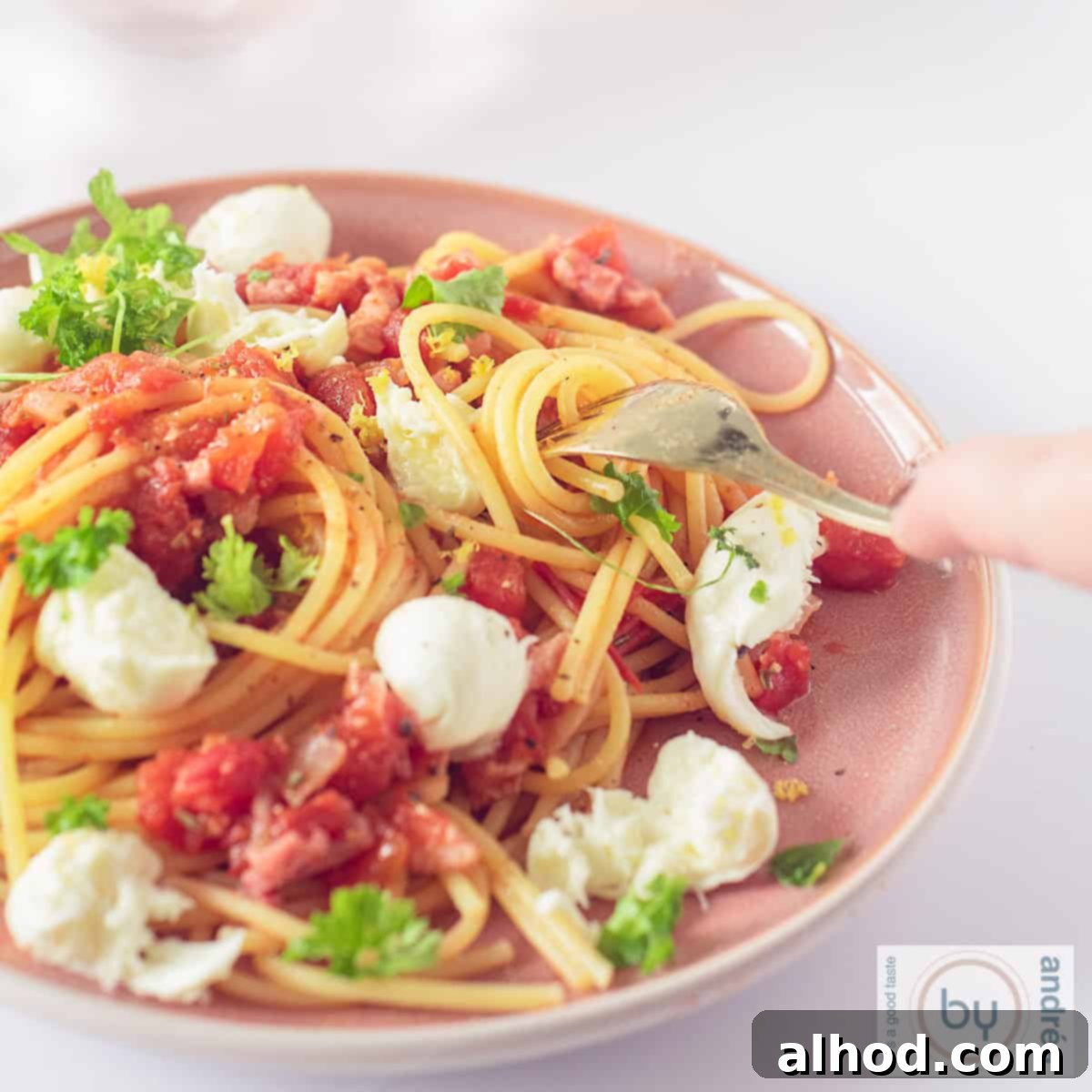 Savory Bacon, Tomato, and Mozzarella Spaghetti 4 A square photo of a pink plate filled with spaghetti, bacon, tomatoes, mozzarella and parsley