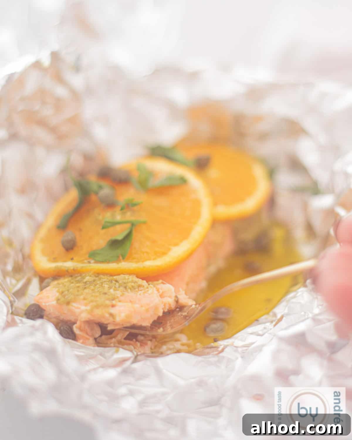 Zesty Salmon Parcel 1 aluminium foil with salmon, orange slices, butter and capers on top.