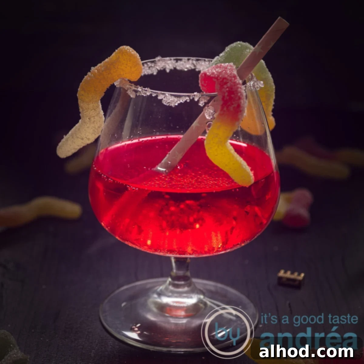Wicked Passoa Brew 6 A square photo with a cocktail in the center with Passoa on a black background. Candy worms climb in it.