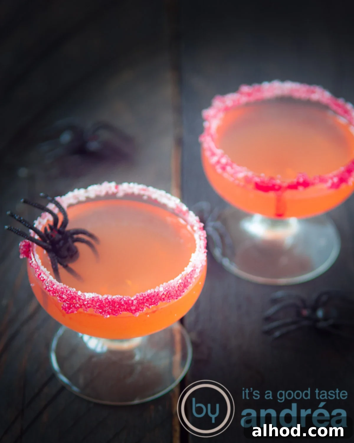 Spooky Cosmopolitan Cocktail 2 two Halloween cocktails with Passoa, Malibu and Orange juice and some spiders across the picture