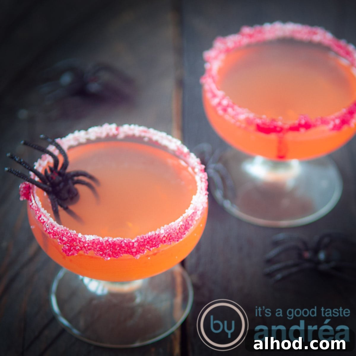 Een vierkante foto met twee glazen gevuld met Halloween cosmpolitan cocktail. Een rode suikerrand.