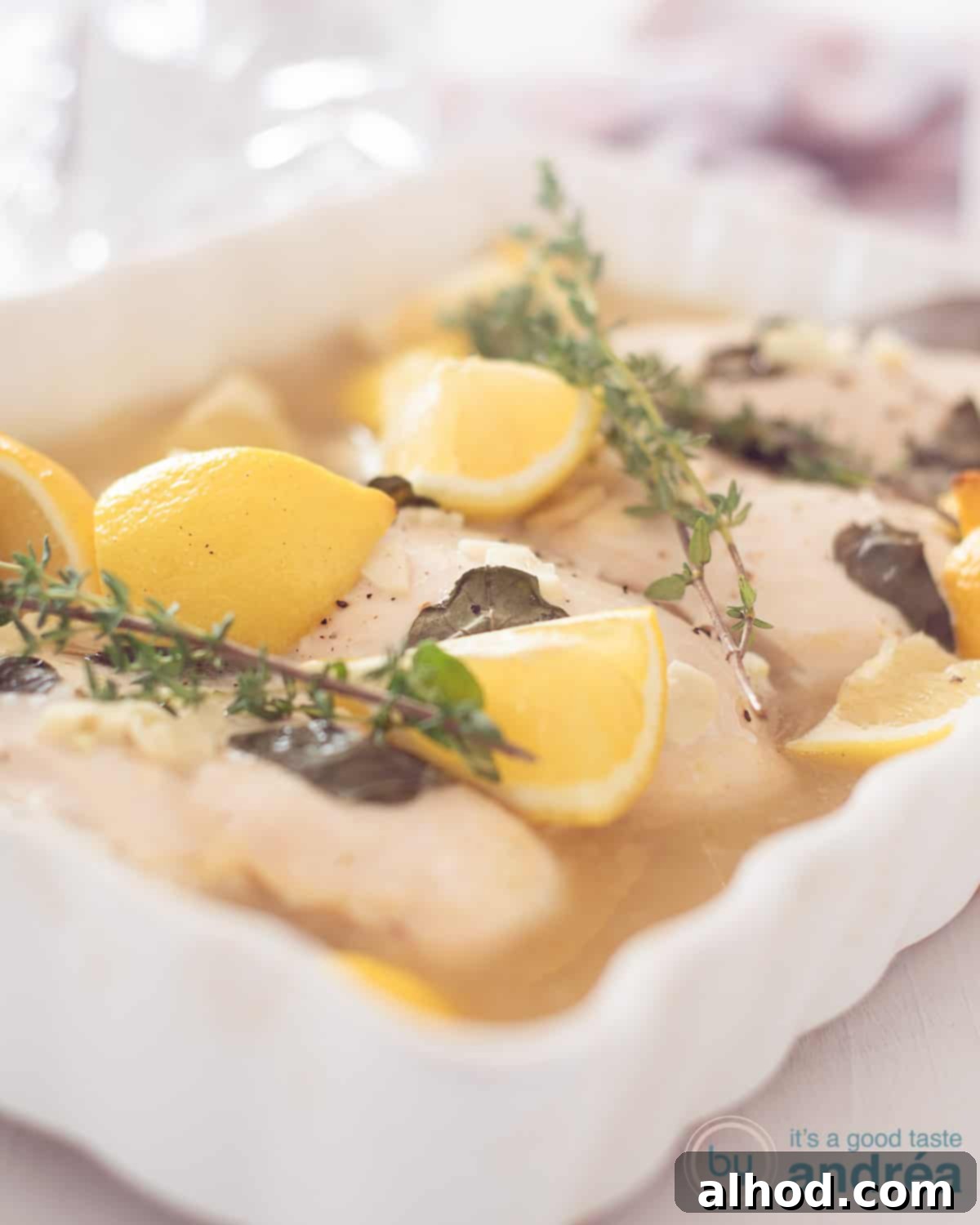 Bright Lemon Thyme Chicken Bake 2 a white casserole with chicken, lemon and thyme. A blue bowl and white cloth