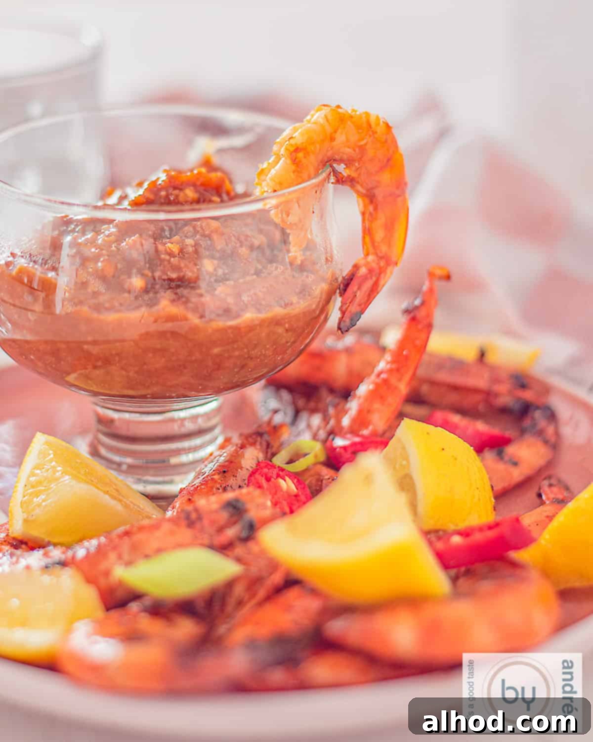 Sizzling Summer Satay Shrimp 2 A photo with a glass filled with satay sauce and grilled shrimps with herbs around it, perfectly capturing the vibrant flavors of the dish.