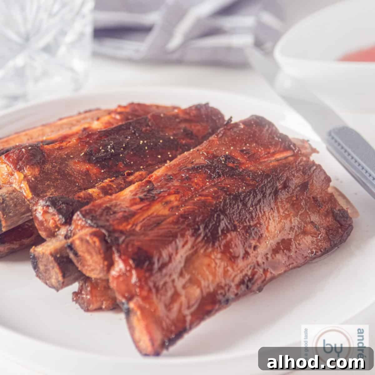A square photo of a plate with a stack of honey kecap whisky ribs, perfectly glazed.