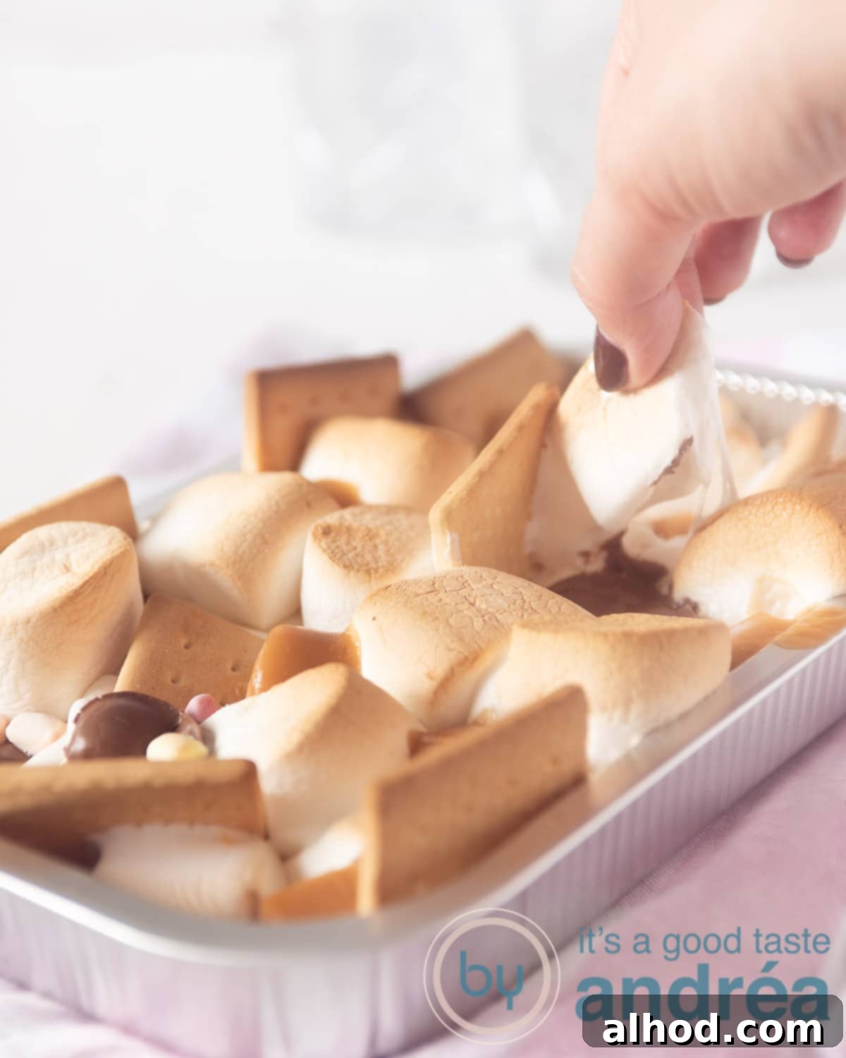 Decadent BBQ S'mores 3 a hand taking out a marshmallow from the aluminium tray