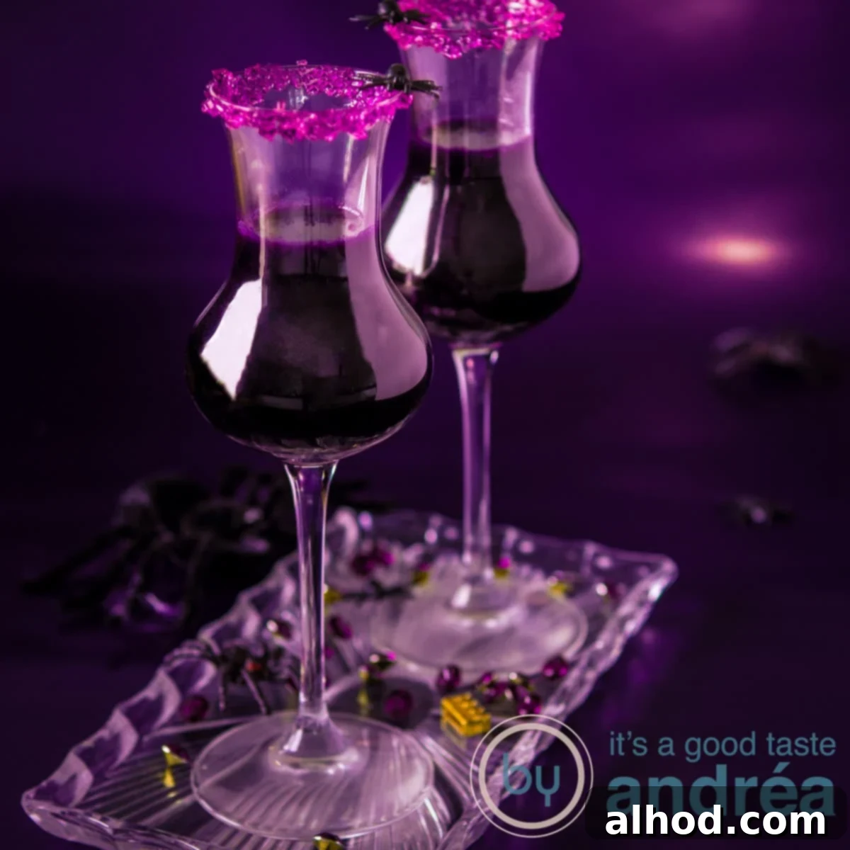 Cauldron Concoction 3 Two cocktail glasses filled with a purple cocktail and a purple sugar rim on a purple background.