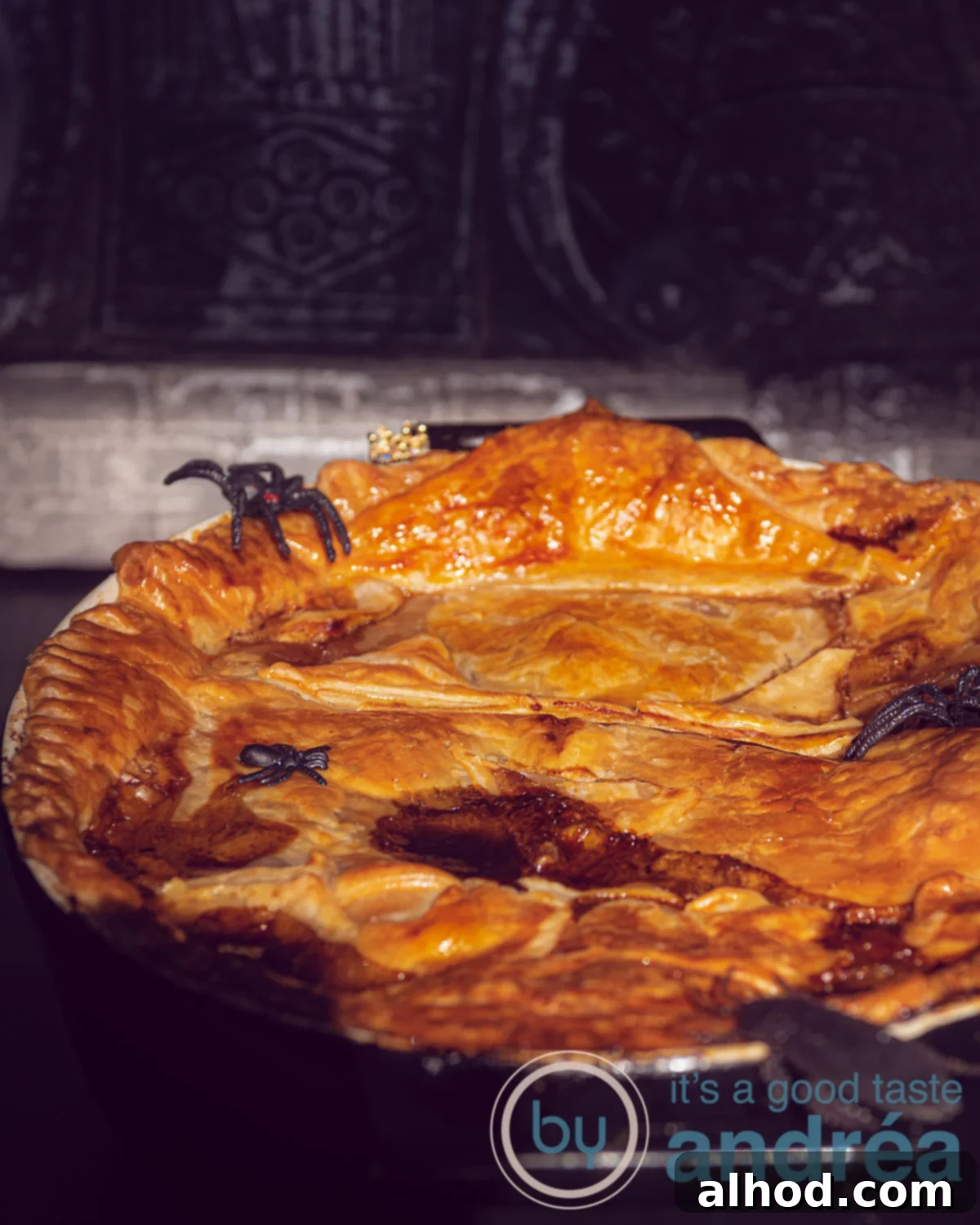 Hearty Guinness Steak Pie 7 A Pie filled with stewed beef, Guinness, vegetables and topped with puff pastry on a dark background. Dressed up in Halloween style.
