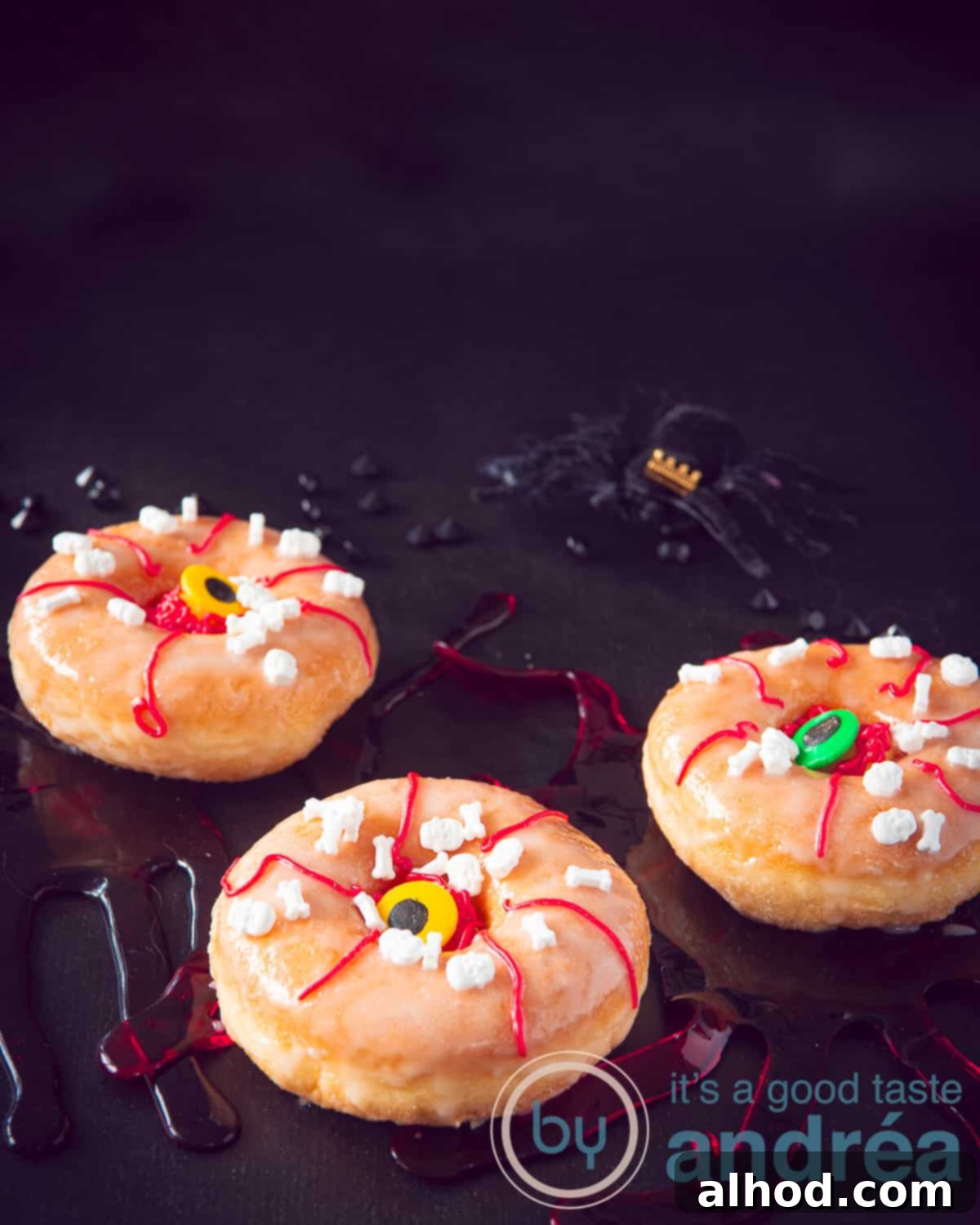 Frightfully Delicious Halloween Donuts 2 A trio of Halloween donuts with a terrible continuous eye on a dark background. One donut has a single eye, another two eyes, and the third is covered in blood-like red icing.