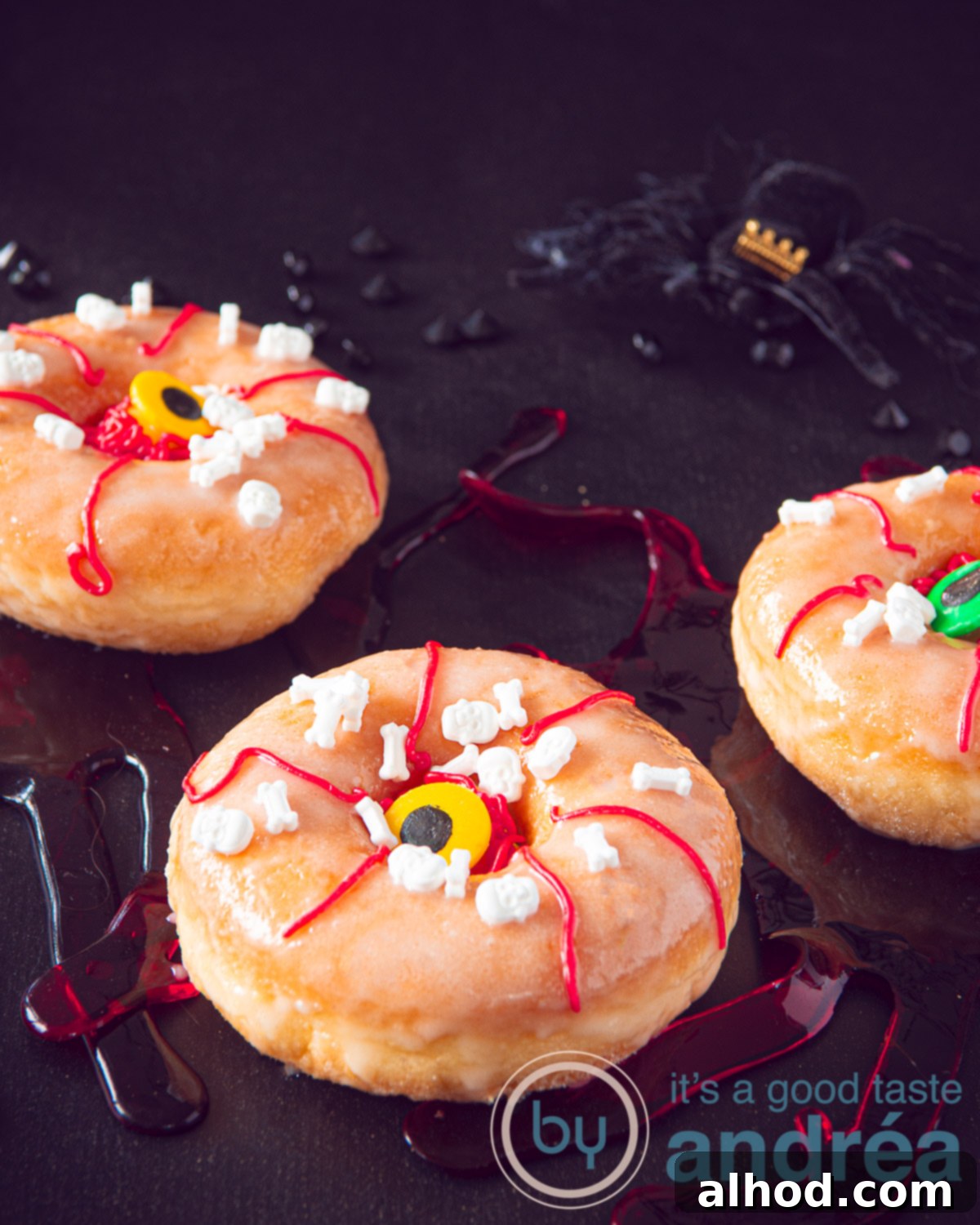 Three Halloween donuts with eyes and red blood stripes on a black background