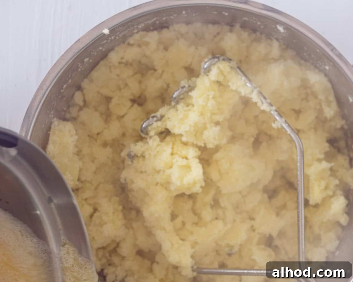 Hearty Beef and Potato Comfort Bake 4 A pot with mashed potatoes, some warm milk is added to the pan.