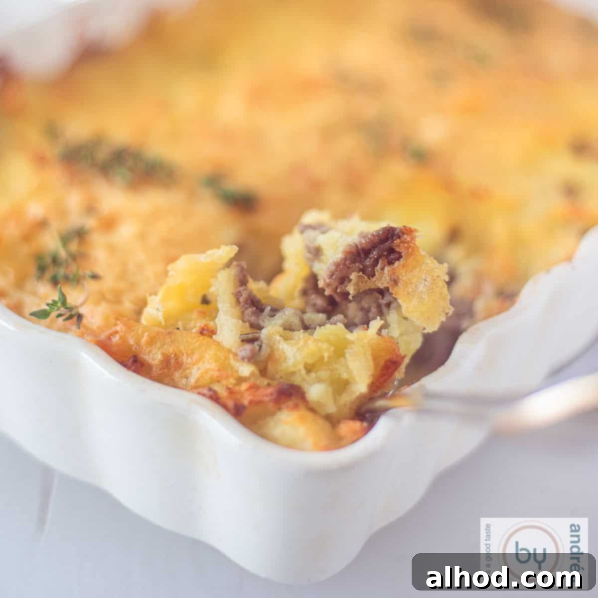 Hearty Beef and Potato Comfort Bake 9 A square picture of part of a casserole with mashed potato gratin and ground beef. A spoon taken a scoop.