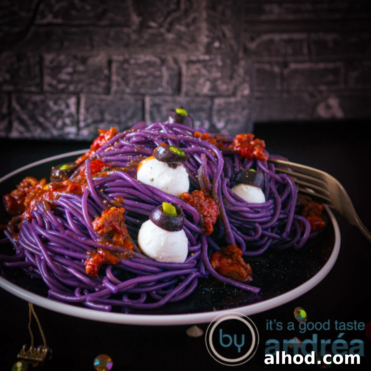 Monster Mash Spaghetti Bolognese 10 A square photo with a plate loaded with purple spaghetti bolognaise and mozzarella eyeballs.