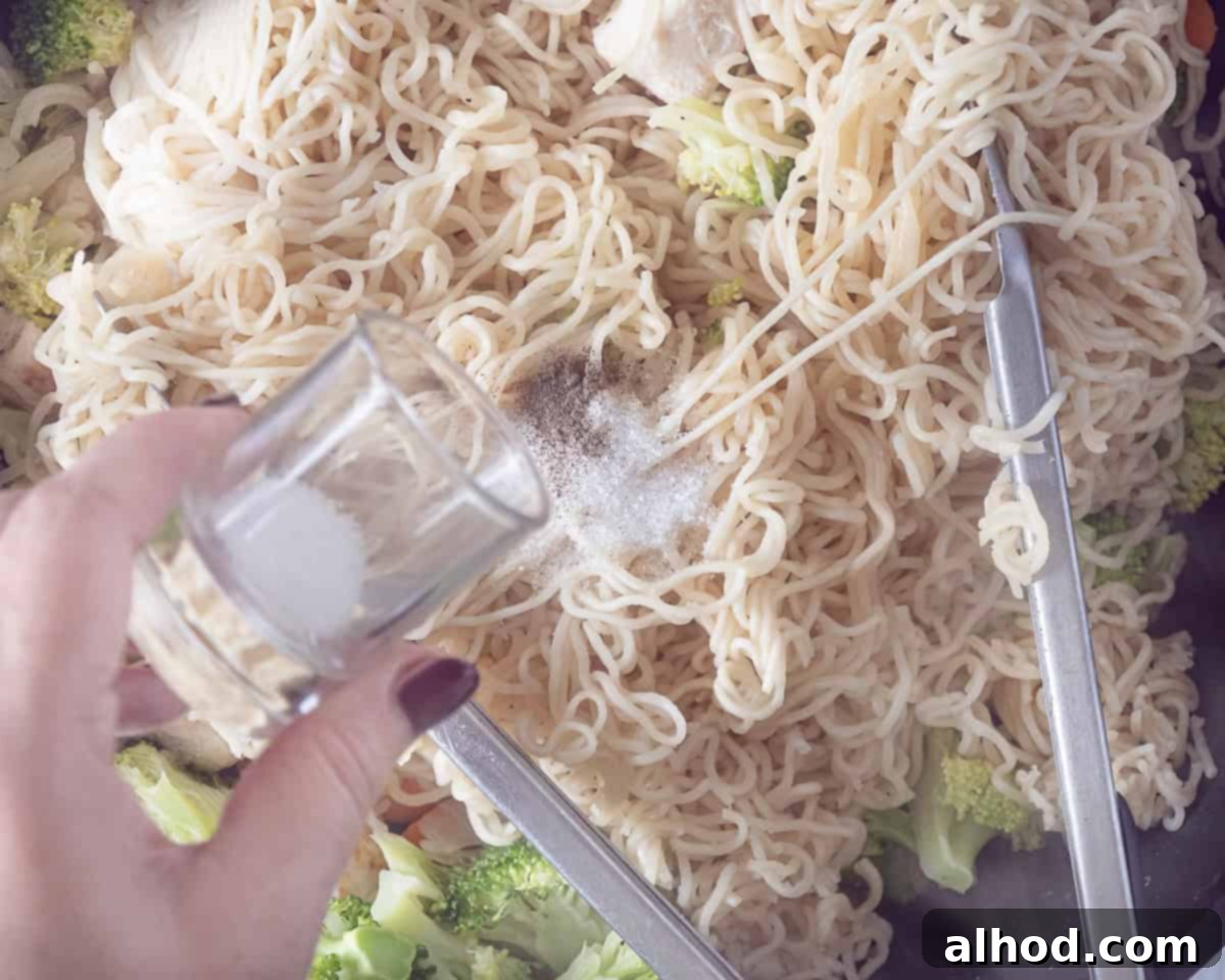 Speedy Chicken Noodle Stir-Fry with Garden-Fresh Veggies 6 A wok containing a delicious stir-fry of noodles, chicken, and vegetables, with a hand sprinkling sugar over the mixture to finish the sauce.