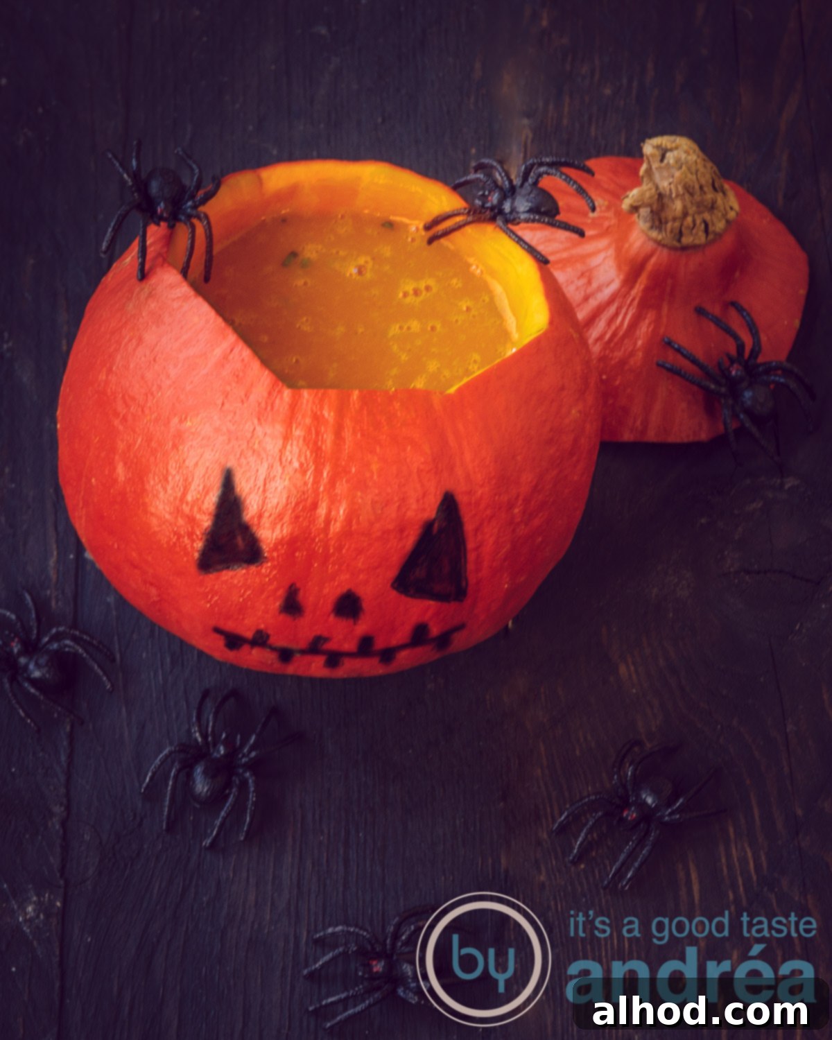 Pumpkin soup served in a hollowed-out pumpkin with a carved Jack-O-Lantern face, garnished with decorative spiders. The rustic and spooky presentation is perfect for a Halloween celebration.