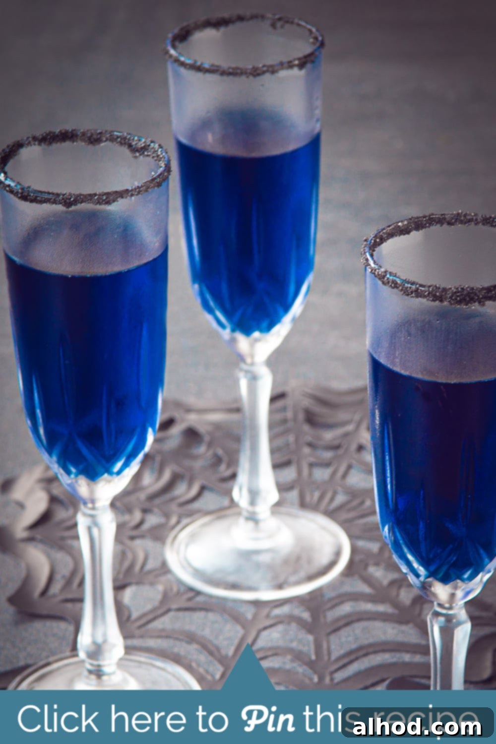 Vibrant blue Halloween Blues Cocktail with a black sugar rim, perfect for a spooky party.