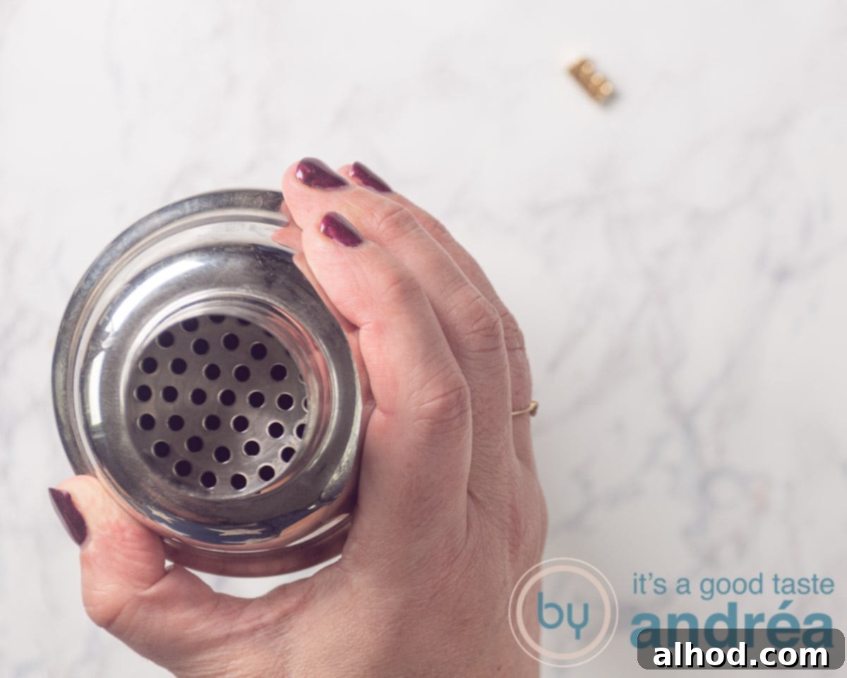 A cocktail shaker with its lid securely on, held firmly by hand, indicating readiness for shaking.